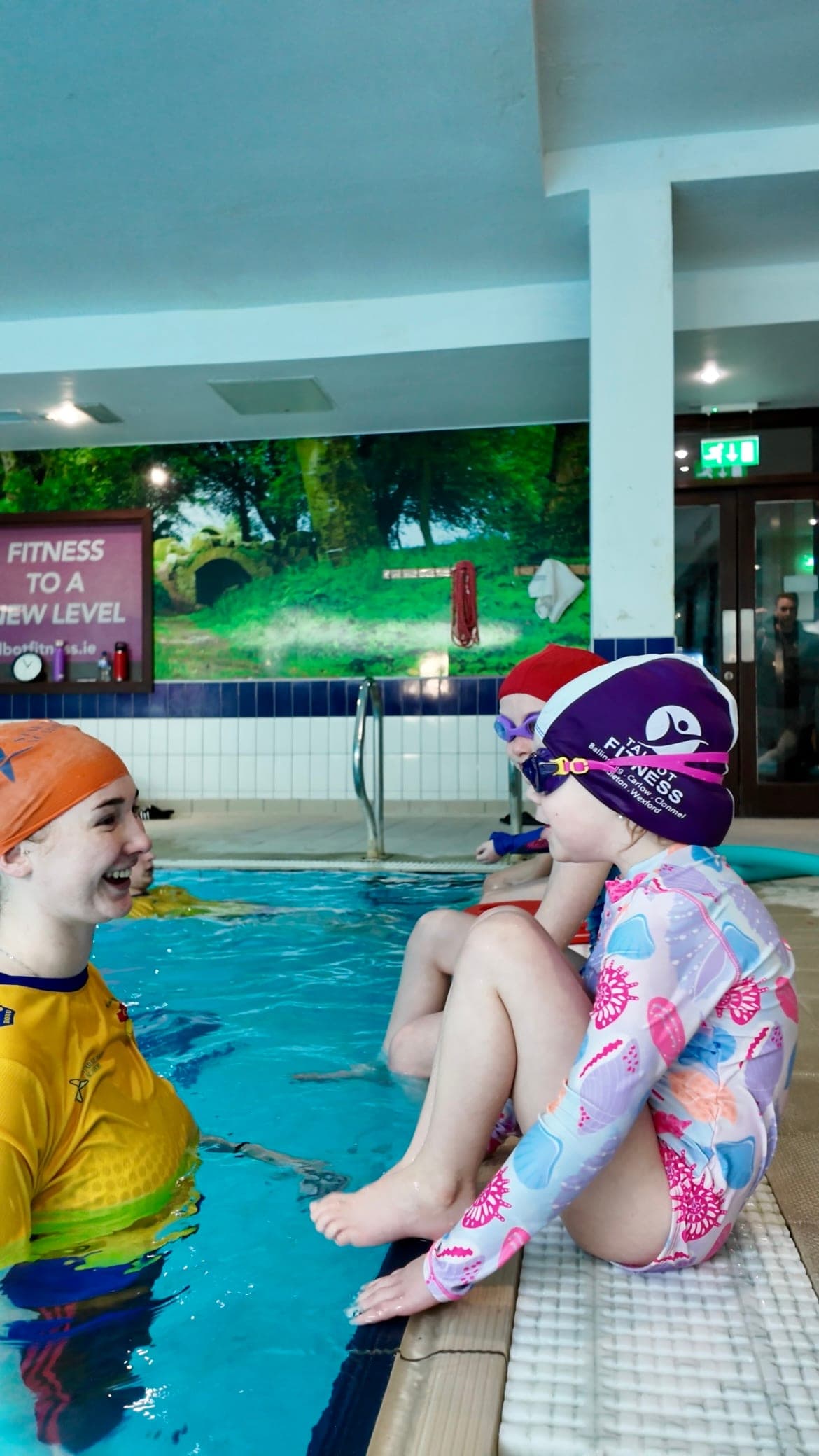 A Star Splash swim teacher laughing with a young swimmer at the edge of the pool